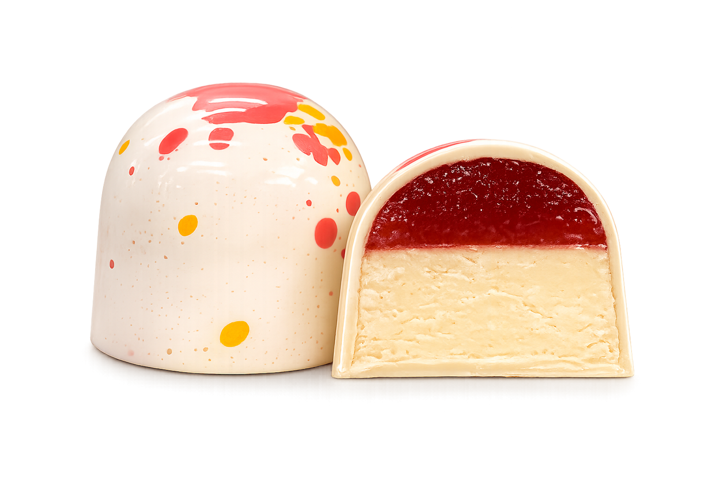 Кондитерський виріб у формі купола з білого шоколаду — «Millennium Craft Strawberry & Lemon with Stevia» від Millennium Chocolate — прикрашений червоними та жовтими бризками; на фото він зображений цілим та розрізаним навпіл, що дозволяє побачити шар полуничного мармеладу поверх кремової білої начинки.